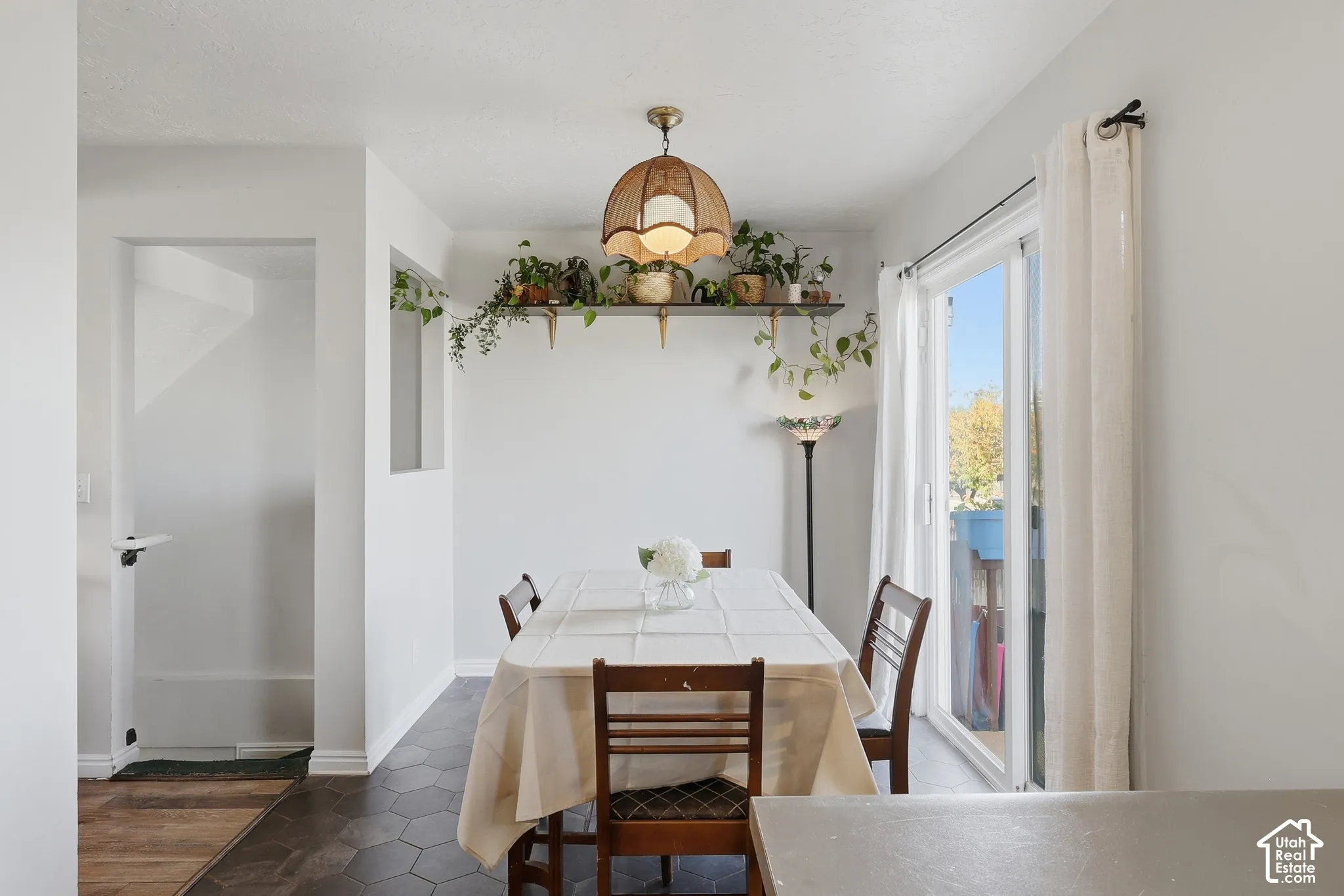 Dining area with hexagonal floor tiles, a sliding glass door, and a decorative wall shelf