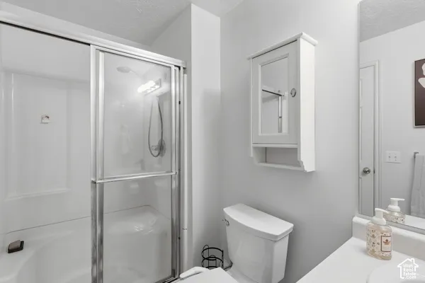 White vanity with an integrated basin, chrome faucet, wall-mounted mirrored medicine cabinet, and a shower-over-tub with sliding glass doors