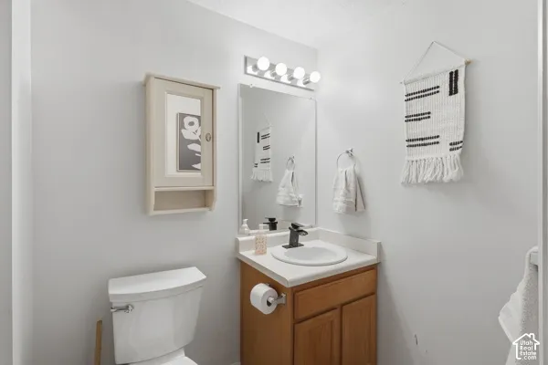 Vanity with wood-finish cabinetry, white countertop, and integrated sink