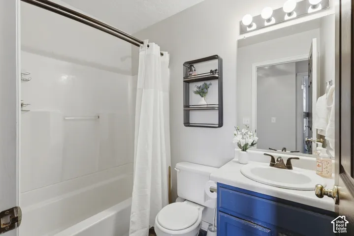 White tub/shower combination, vanity with a rectangular sink, wall-mounted mirror, and vanity lighting
