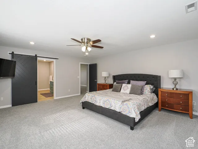 Spacious master bedroom featuring new light gray carpeting, custom wood blinds, and neutral wall tones.