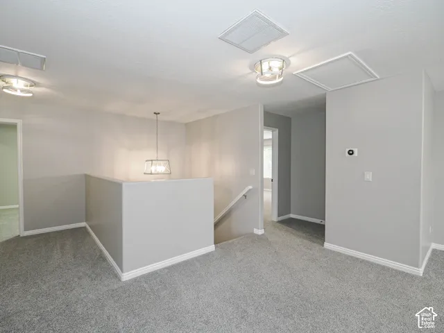 Carpeted landing area featuring a contemporary pendant light fixture, recessed lighting, baseboard trim, and light gray wall paint.