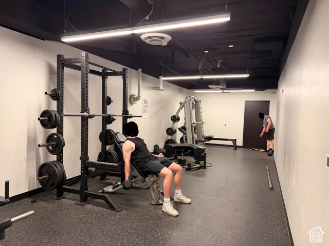 Fitness amenity featuring a weight rack, exercise bench, and rubberized flooring