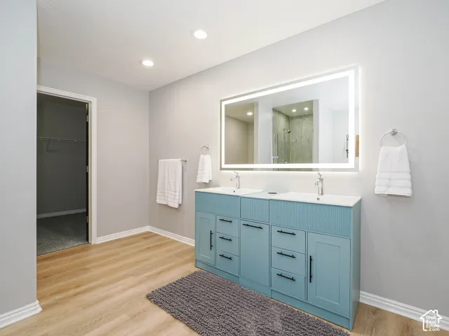 Newly updated master bathroom with double vanity with recessed docking station with wireless charging, light blue cabinetry with matte black hardware, and new large heated anti-fog mirror with lighting.