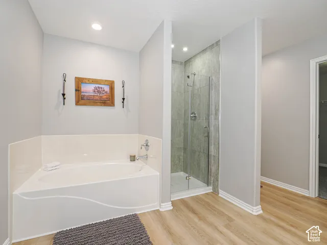 Corner soaking tub featuring a chrome faucet and a tiled shower with a glass enclosure.