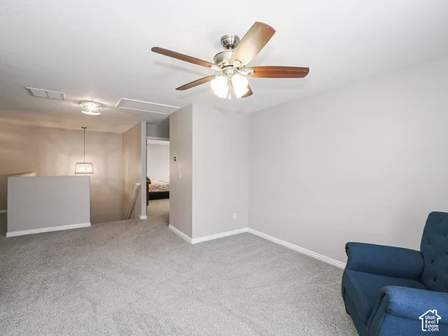 Carpeted loft/potential bedroom 5 featuring a Hunter ceiling fan with light, and a contemporary pendant light fixture.