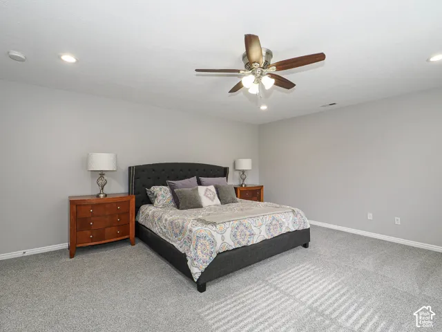 Spacious master bedroom featuring newly painted light gray walls, recessed led lighting, hunter ceiling fan, and new gray carpeting.