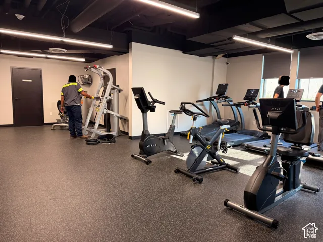 Fitness area featuring specialized flooring, linear overhead lighting, and dedicated equipment