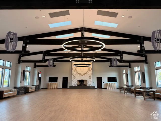 Vaulted ceiling with exposed beams, multiple skylights, and contemporary circular lighting fixtures, ginormous fireplace with book matched stone chimney