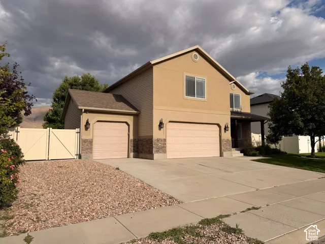 Two-story stucco exterior with a covered porch entry, three car garage, extra parking, and RV parking behind the fence with a 50-amp hookup.