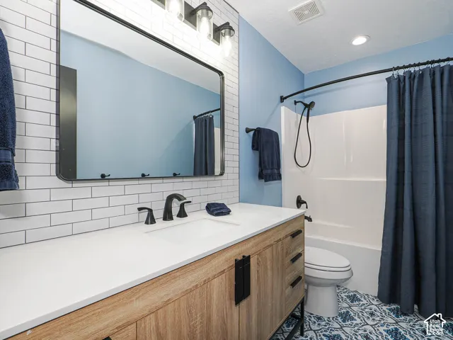 Bathroom featuring a wood-finish vanity with a white countertop, subway tile backsplash, and a framed mirror.
