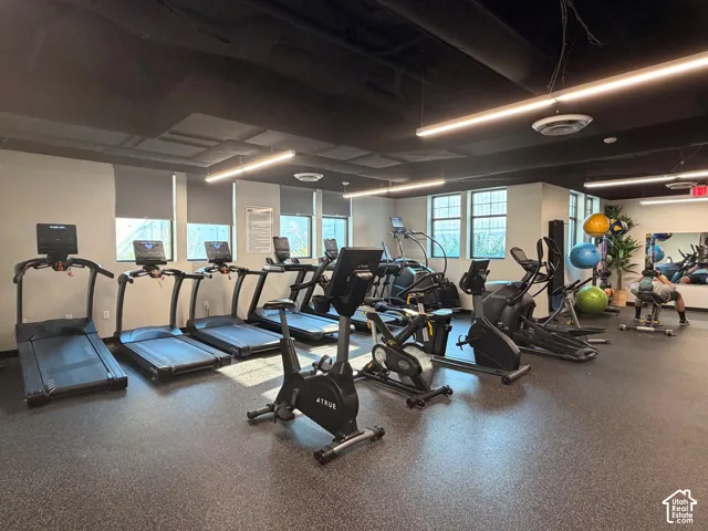 Fitness center with multiple exercise machines, dedicated flooring, recessed lighting, and natural light from window fixtures