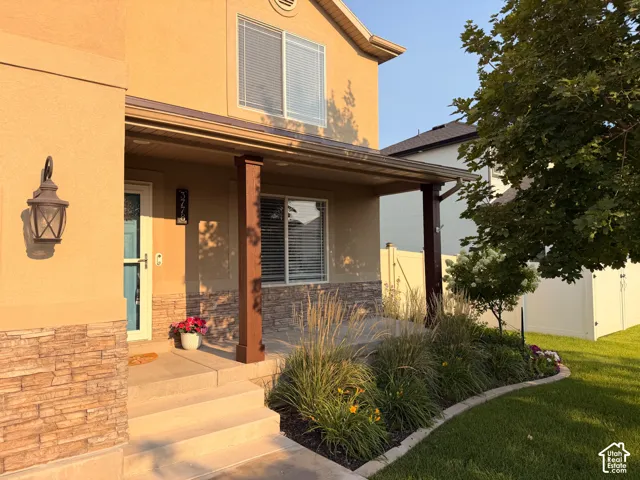Covered front porch with solid wood posts, stone accents, metal accent roof, and mature landscaping.