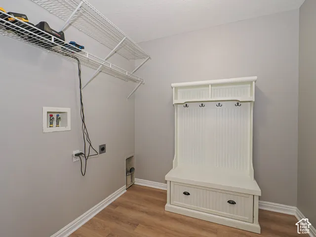 Laundry area featuring wood-finish flooring, light grey walls, and white baseboards.