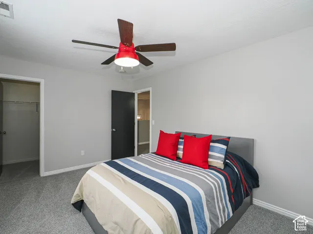 Bedroom 2 with neutral gray walls, new gray carpet flooring, custom wood blinds, Hunter ceiling fan, and a large walk-in closet.