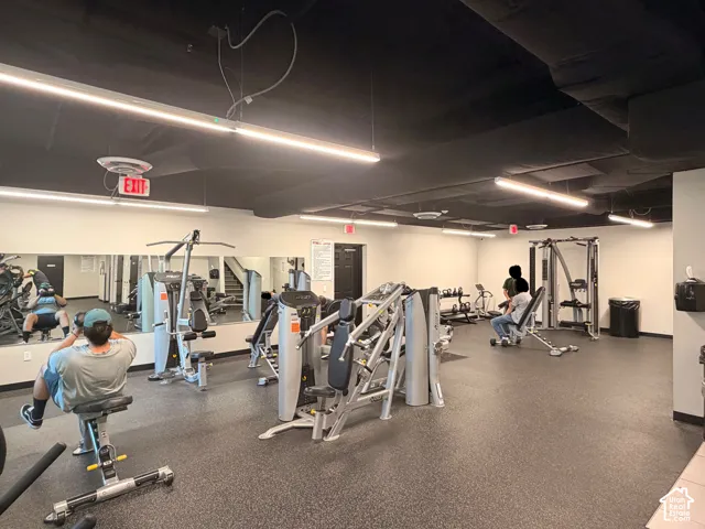 Fitness center featuring extensive exercise equipment, mirrored wall, and durable rubber flooring