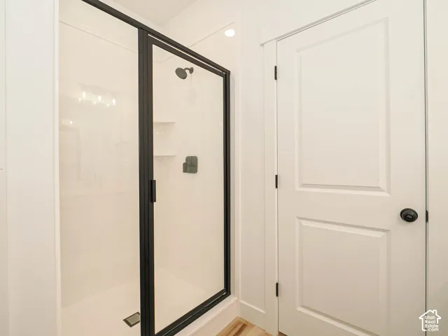 Walk-in shower with black-framed glass enclosure, integrated shelving, and matte black fixtures
