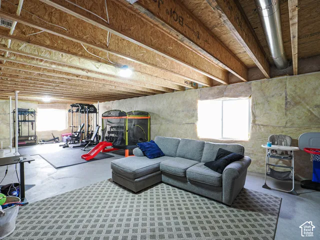 Basement space featuring exposed ceiling joists, concrete flooring, and an egress window