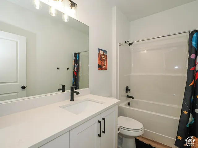 White vanity with an integrated sink and matte black faucet, full-width mirror, and a white bathtub with a shower