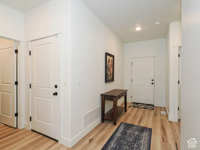 Wood-finish flooring throughout the space, featuring white paneled doors with black hardware, and recessed ceiling lighting