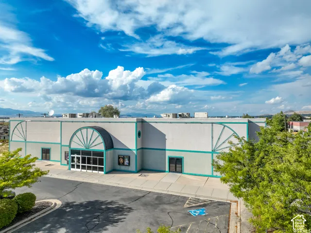 Commercial building with a prominent arched entrance, large windows, and a paved parking area
