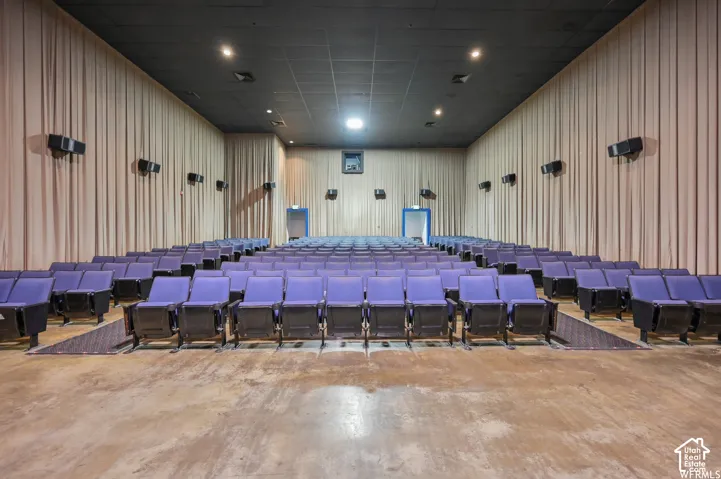 Tiered seating with purple upholstered chairs, acoustic wall coverings, a dark ceiling with recessed lighting, and wall-mounted speakers