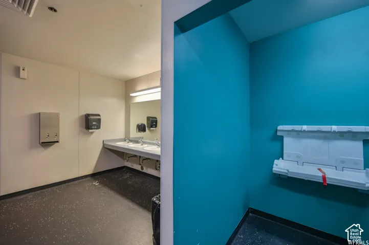 Three basin vanity with wall-mounted mirror, recessed lighting, and durable flooring