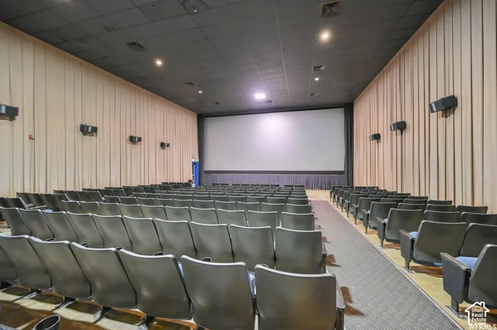 Large projection screen framed by dark curtains, auditorium seating, dark ceiling, and light-colored wall panels