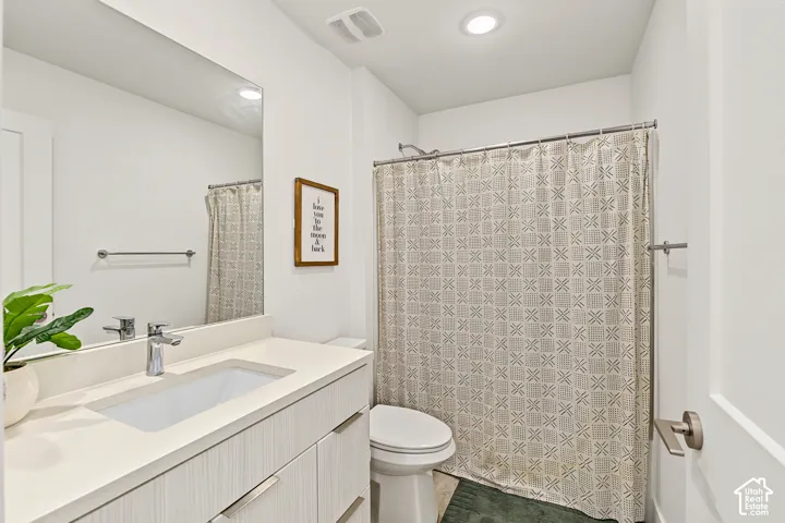 Modern bathroom featuring a floating vanity with an expansive countertop, vessel sink, and contemporary chrome faucet