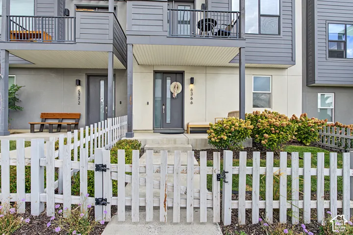 Contemporary exterior design featuring a white picket fence, concrete walkway, and established plantings