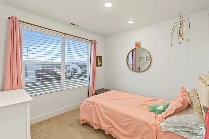 Recessed lighting, large window with blinds, carpeted flooring, and white walls