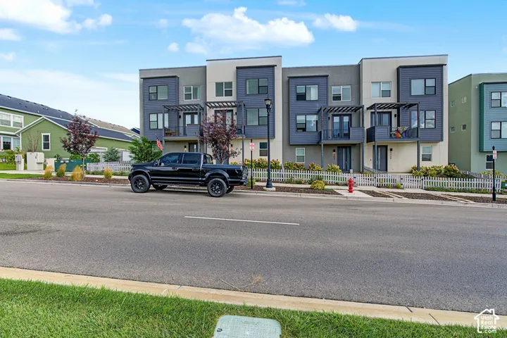 Modern townhome exterior featuring multi-toned siding, integrated balconies with privacy screening, and picket fencing