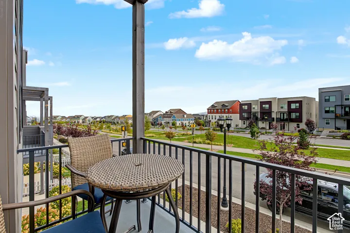 Exterior balcony with black metal railing and overhead wood-finish beams