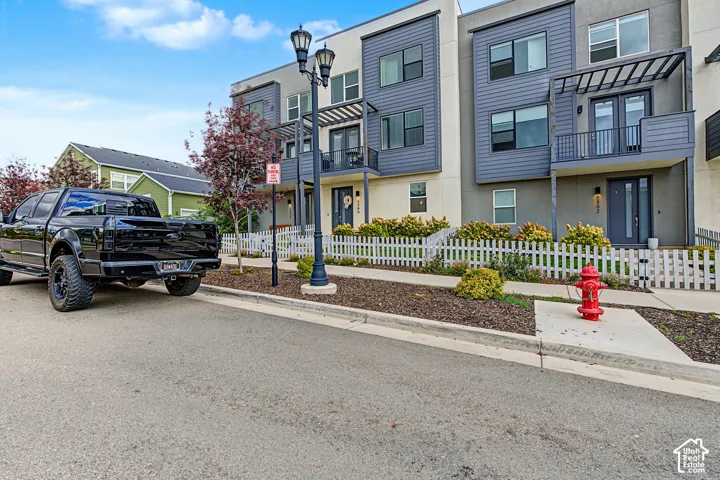 Modern multi-story exterior with varied siding, front balcony, and contemporary light fixtures