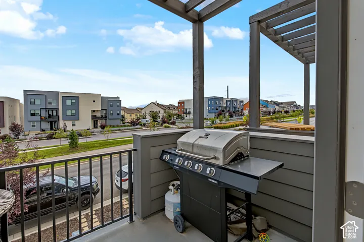 Outdoor balcony featuring a wood pergola, dark metal railing, and gray siding