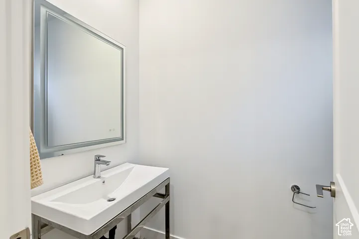 White floating rectangular sink with a single-handle chrome faucet, set on a chrome-finish vanity frame, complemented by a rectangular wall-mounted mirror