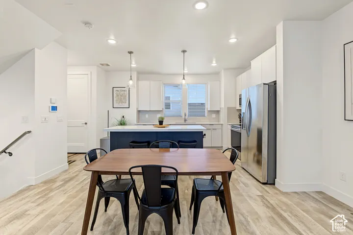 Open-concept kitchen featuring an island with pendant lighting, stainless steel appliances, and white cabinetry