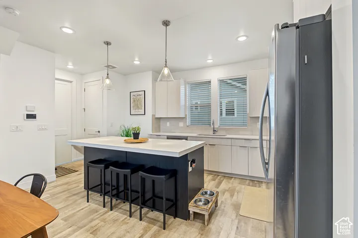 Kitchen featuring a central island with countertop seating, light wood-finish flooring, recessed lighting, and pendant lighting