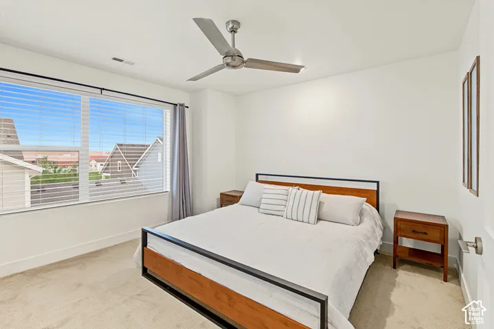 Expansive window with blinds, ceiling fan with light, and light-toned wall-to-wall carpeting