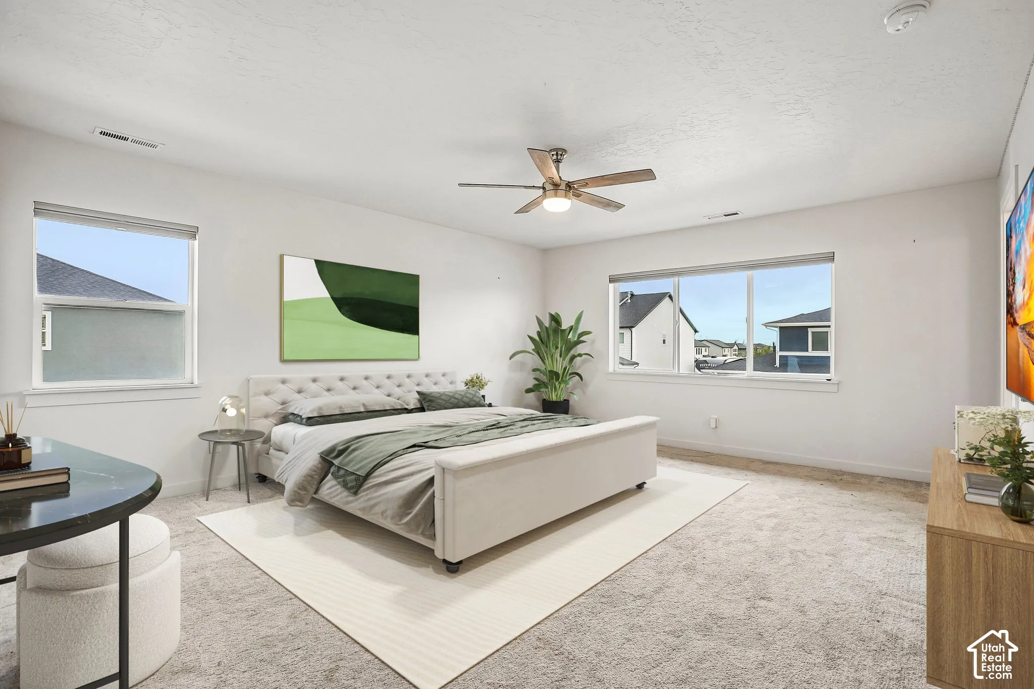 Expansive room with neutral carpeting, multiple windows providing natural light, and a ceiling fan