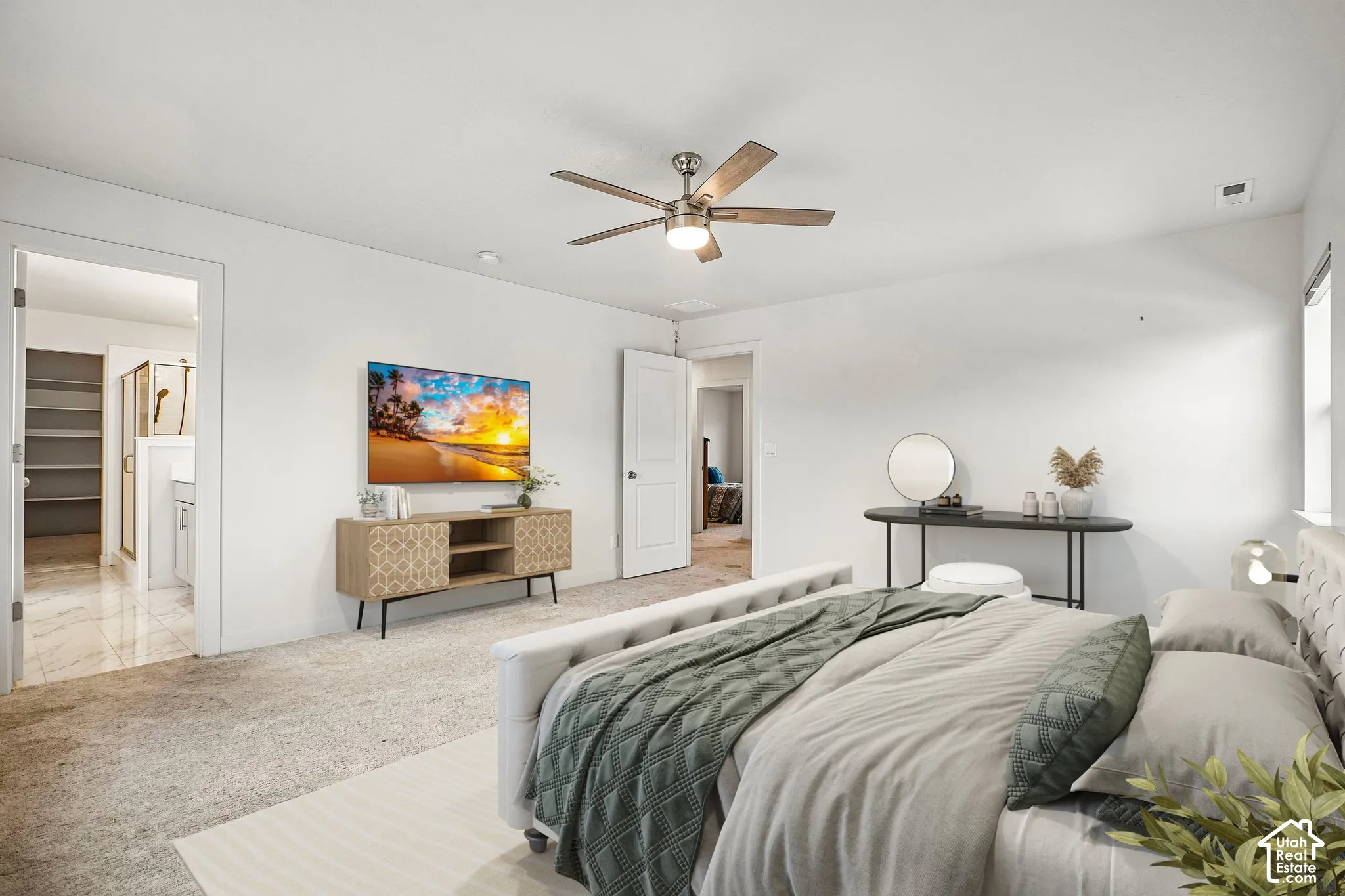 Tray ceiling with a ceiling fan, carpet flooring, window, and an attached bathroom with tiled flooring and built-in shelving