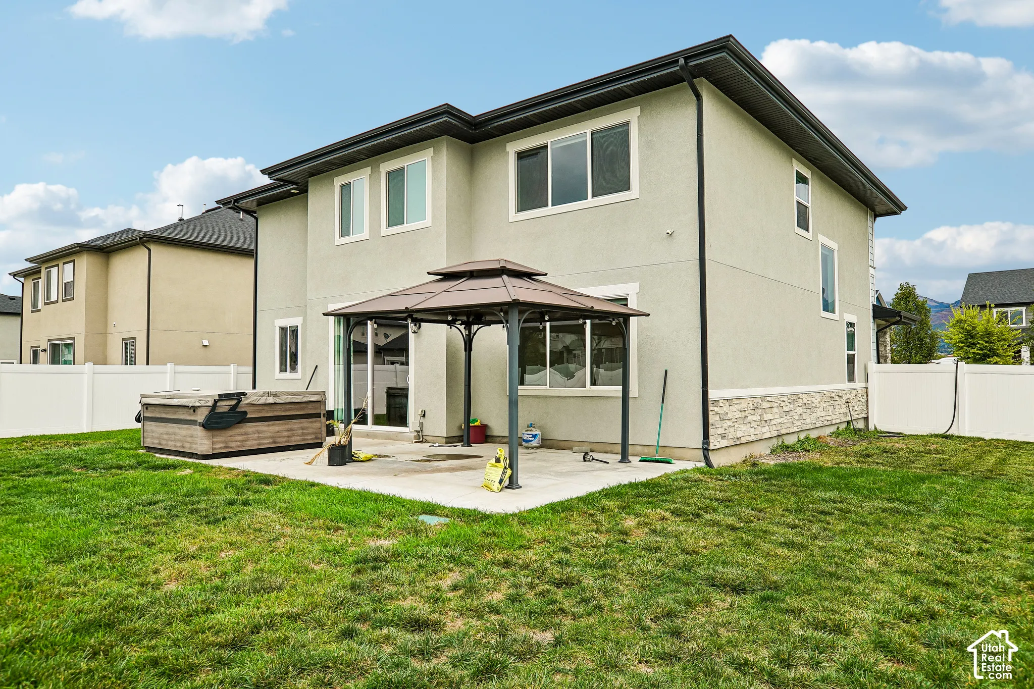 Expansive backyard featuring a manicured lawn, concrete patio, and built-in gazebo