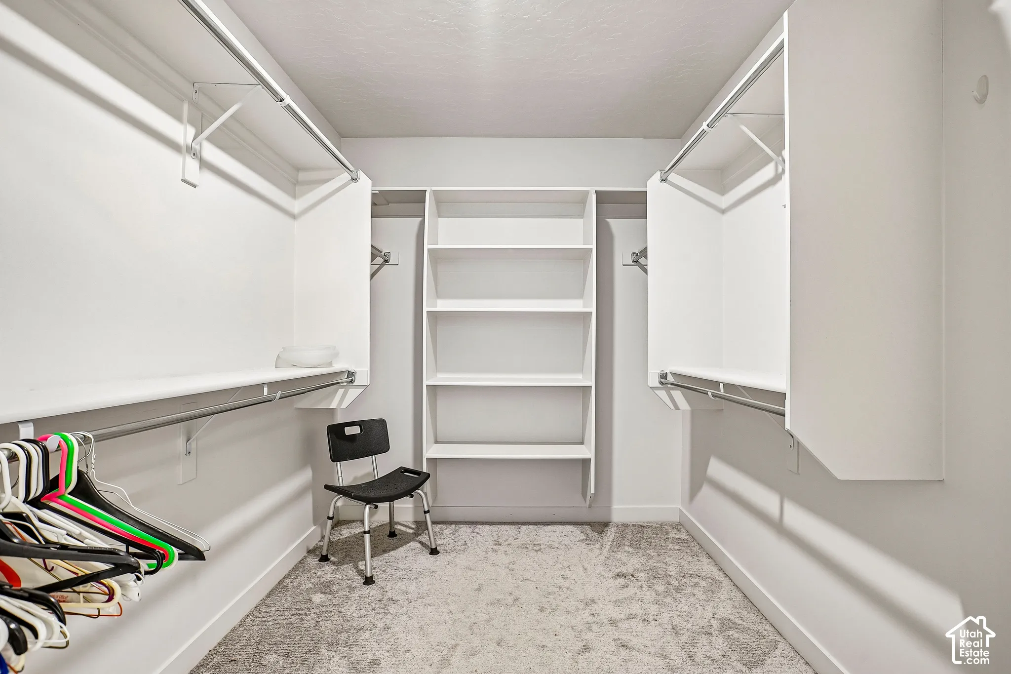 Walk-in closet with carpet flooring, built-in shelving, and multiple hanging rods for organization