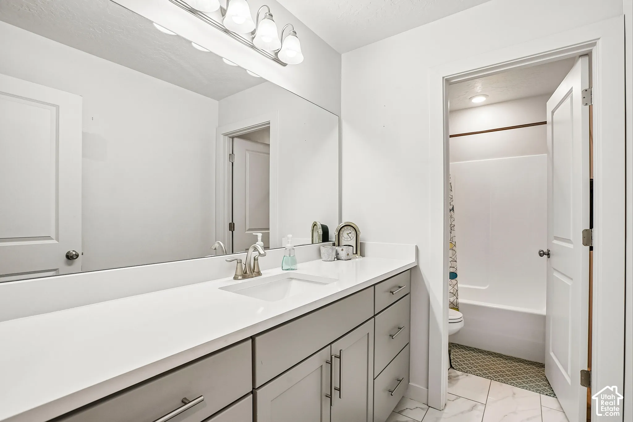 Vanity with a long countertop, undermount sink, and light gray cabinetry
