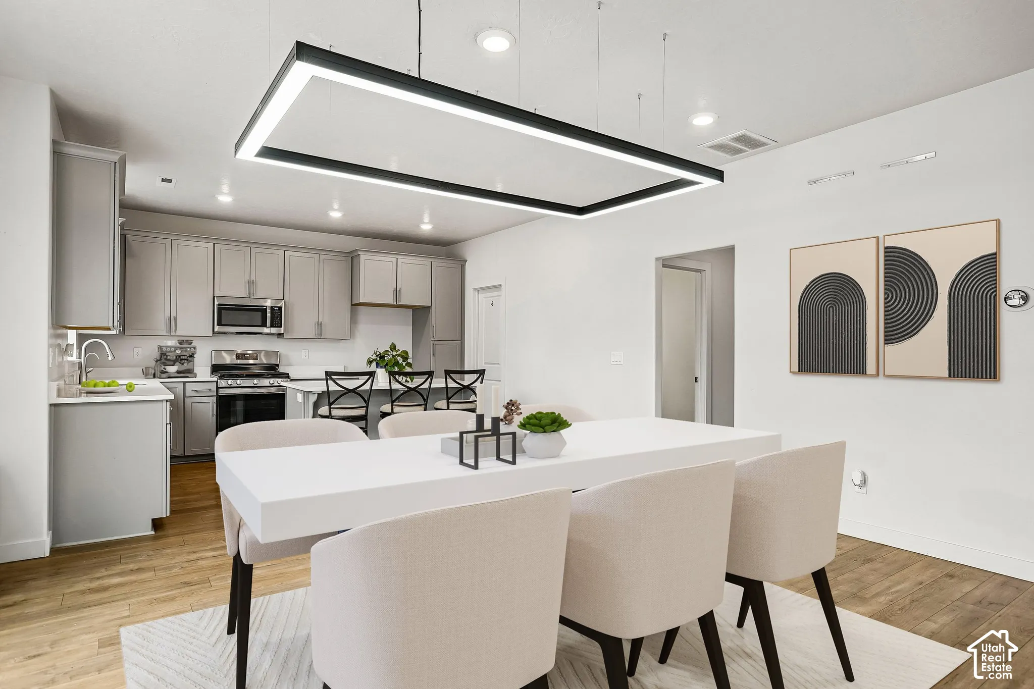 Open-concept dining and kitchen area featuring wood-finish flooring, recessed lighting, and a linear pendant light fixture