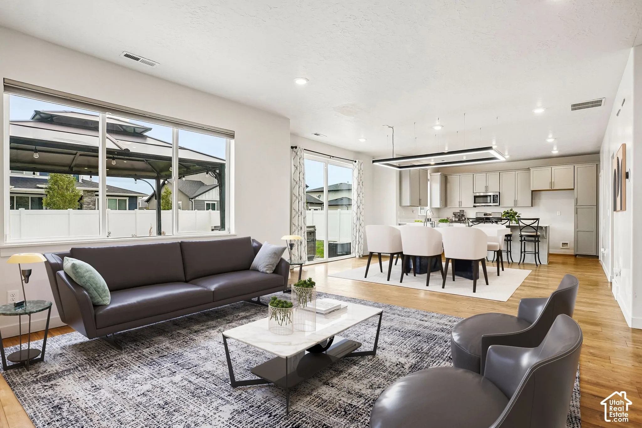 Open-concept living area featuring wood-finish flooring, recessed lighting, and a kitchen with stainless steel appliances
