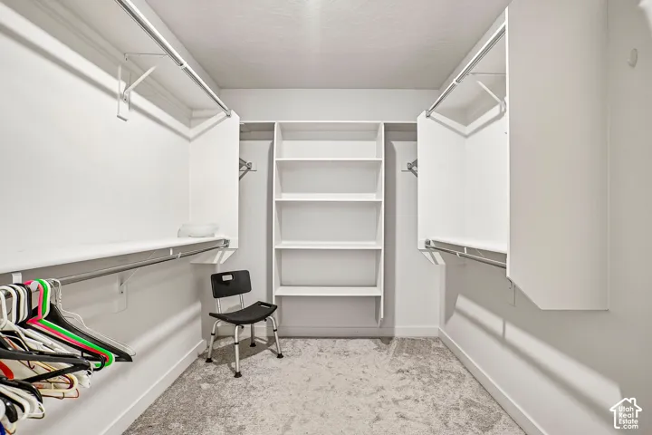 Walk-in closet with carpet flooring, built-in shelving, and multiple hanging rods for organization