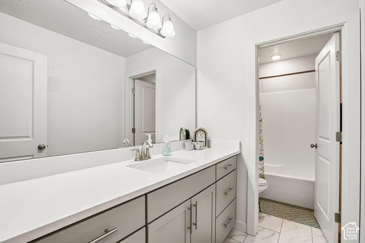 Vanity with a long countertop, undermount sink, and light gray cabinetry