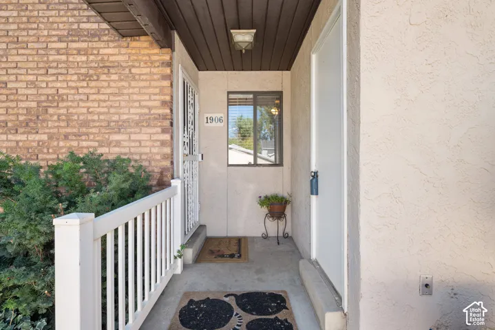 Brick exterior detailing, stucco facade, white railing, covered entryway, and exterior lighting