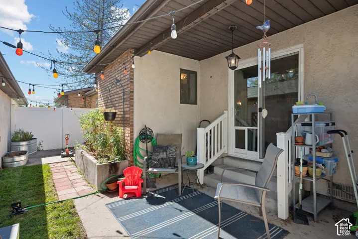Private patio featuring a sliding glass door, white railing, and exterior lighting